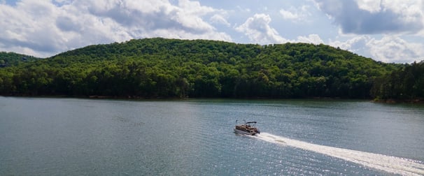 A pontoon boat on a lake drifts across the waters