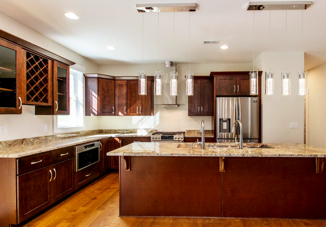 A modern kitchen with black cabinets, stainless steel appliances, and granite countertops