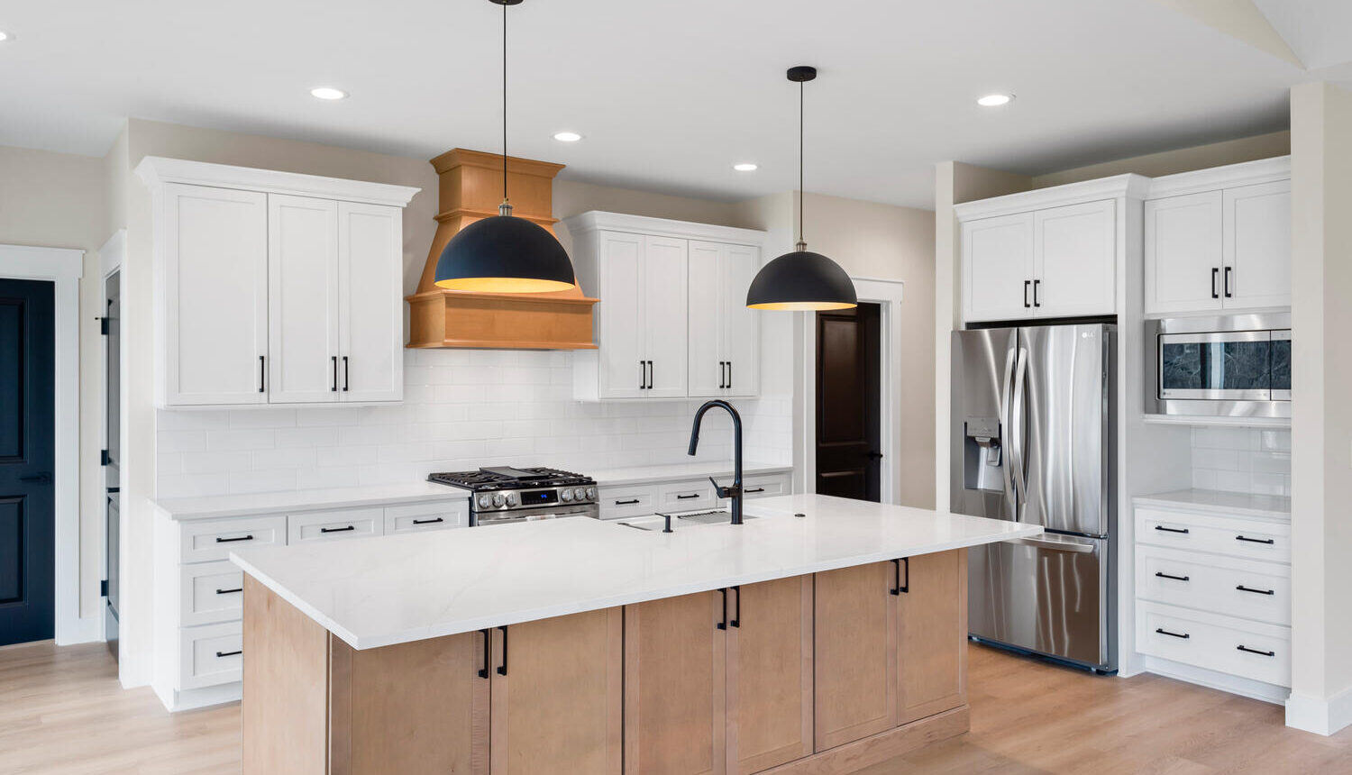 A kitchen layout in a single family home with white cabinetry and black design elements.